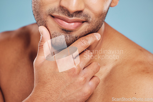 Image of Hands, face and beauty with a man model posing in studio on a blue background for skincare or grooming. Cleaning, bathroom and wellness with a young male indoors to promote a natural cosmetic product