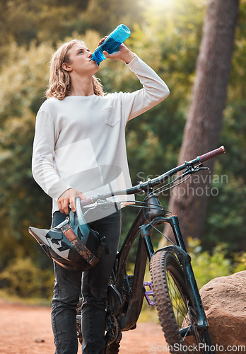 Image of Drinking water, bike sport and man on an outdoor forest nature trail for exercise and sports. Bicycle training, cycling workout and fitness of an adventure athlete on a woods dirt road for wellness