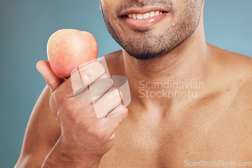 Image of Hand, apple and beauty with a man model in studio on a blue background for heathy eating or diet. Food, fruit and health with a young male posing with a nutrition snack for natural care or vitamins