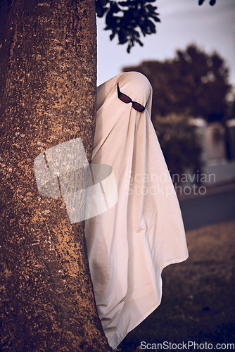 Image of ghost costume, halloween and sunglasses in nature park outdoors. Funny horror dress up, spooky holiday celebration and creative scary mystery spirit design or hiding ghoul with glasses for carnival