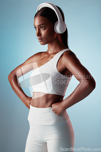 Image of Fitness, studio and woman streaming music ready to start training, workout and body exercise in India, Mumbai. Focus, blue background and healthy girl athlete listening to radio or mindset podcast