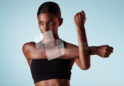 Image of Fitness, studio and woman stretching shoulder and arms in a warm up to start training, workout and cardio exercise. Focus, wellness and healthy young sports girl relaxing her strong body muscles