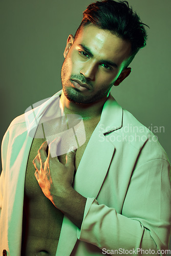 Image of Beauty, green lights and portrait of sexy man from India touching bare chest in creative studio shoot. Fashion, neon light and professional male model, single Indian man with seductive and sexy style