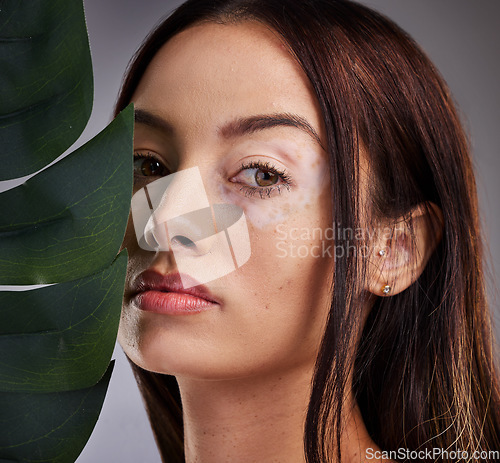 Image of Beauty, leaf and woman with vitiligo in studio for wellness, skincare and luxury grooming on grey background mockup. Portrait, plant and face of dermatology model relax with natural facial product