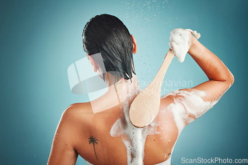 Image of Skincare, back and woman in a shower for cleaning, hair and wellness against a blue background mockup. Beauty, brush and skin, scrub and exfoliate by girl model in a studio, relax and washing