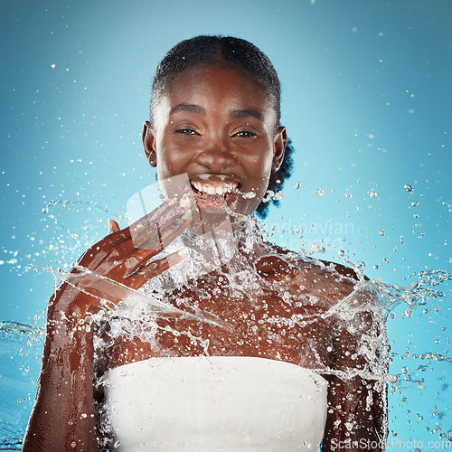 Image of Beauty, splash and black woman in studio for cleaning, skincare and facial on blue background mockup. Water, face and portrait of girl model happy, relax and smile during grooming, hygiene and shower