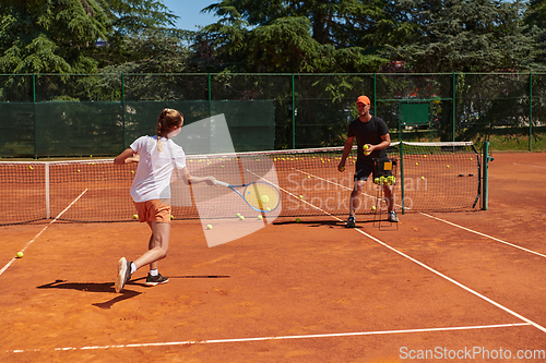 Image of A professional tennis player and her coach training on a sunny day at the tennis court. Training and preparation of a professional tennis player