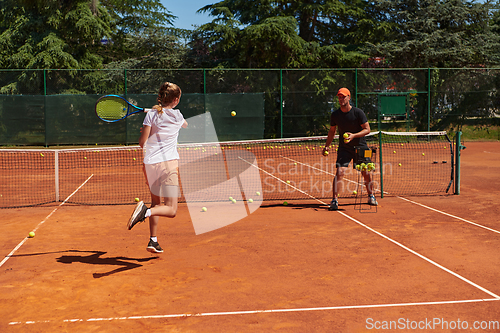 Image of A professional tennis player and her coach training on a sunny day at the tennis court. Training and preparation of a professional tennis player