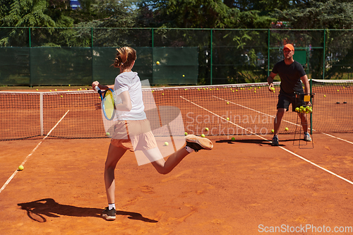 Image of A professional tennis player and her coach training on a sunny day at the tennis court. Training and preparation of a professional tennis player