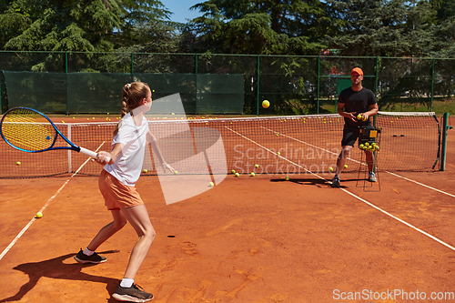 Image of A professional tennis player and her coach training on a sunny day at the tennis court. Training and preparation of a professional tennis player