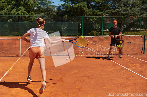 Image of A professional tennis player and her coach training on a sunny day at the tennis court. Training and preparation of a professional tennis player