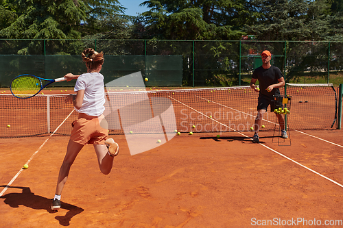 Image of A professional tennis player and her coach training on a sunny day at the tennis court. Training and preparation of a professional tennis player