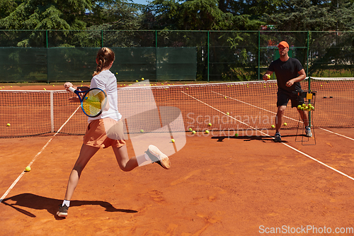 Image of A professional tennis player and her coach training on a sunny day at the tennis court. Training and preparation of a professional tennis player