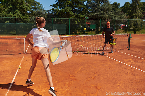 Image of A professional tennis player and her coach training on a sunny day at the tennis court. Training and preparation of a professional tennis player