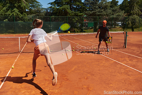 Image of A professional tennis player and her coach training on a sunny day at the tennis court. Training and preparation of a professional tennis player