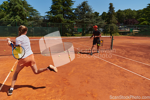 Image of A professional tennis player and her coach training on a sunny day at the tennis court. Training and preparation of a professional tennis player