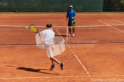 Image of A professional tennis player and her coach training on a sunny day at the tennis court. Training and preparation of a professional tennis player