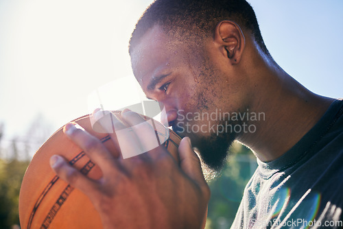 Image of Black man, basketball and kiss for sports love, passion or dedication in motivation, good luck or praise on the court. African American male basketball player kissing lucky ball for score or point