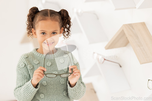 Image of Girl, child and glasses for vision, shopping and buying spectacles in an optometry store. Retail, choice and eyewear for small kid choosing eyeglasses for eyesight and opthalmology