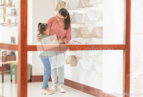 Image of Mother, girl and shopping, glasses and optometrist for lense, frame and vision together in retail store. Woman customer buy prescription with child for eyesight in optometry shop to choose or choice