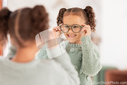 Image of Children, mirror and girl with glasses at optometry store, testing or shopping for new eyewear. Vision, choice and happy kid trying spectacles or lenses at optics shop while looking at reflection.