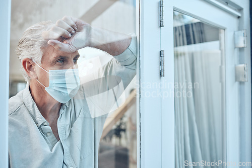 Image of Lonely, face mask and senior man in the house for quarantine, protection and isolation during pandemic. Depression, frustrated and sad elderly guy with covid looking outside the window at his home.