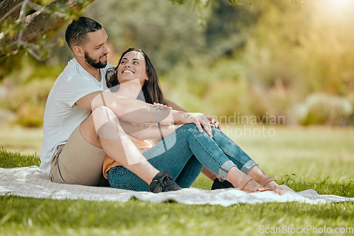 Image of Couple relax on grass, outdoor picnic in park and love sitting on blanket in Miami garden under a tree. Romantic date in spring, woman smile at happy boyfriend or summer holiday together in sunshine