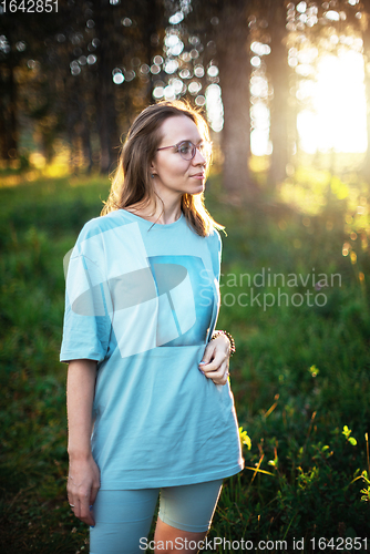 Image of woman walking early in summer forest area
