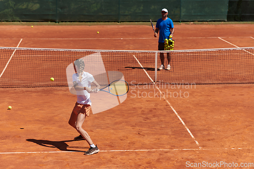 Image of A professional tennis player and her coach training on a sunny day at the tennis court. Training and preparation of a professional tennis player