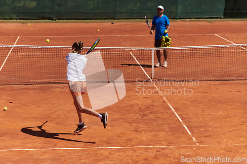 Image of A professional tennis player and her coach training on a sunny day at the tennis court. Training and preparation of a professional tennis player