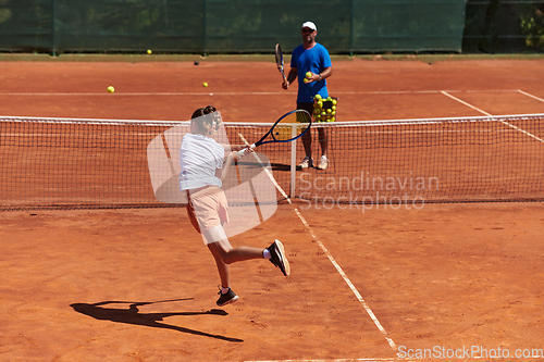 Image of A professional tennis player and her coach training on a sunny day at the tennis court. Training and preparation of a professional tennis player