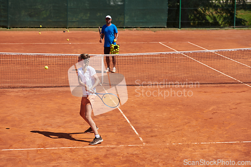 Image of A professional tennis player and her coach training on a sunny day at the tennis court. Training and preparation of a professional tennis player