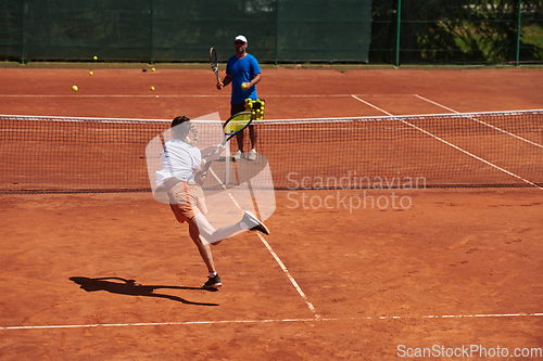 Image of A professional tennis player and her coach training on a sunny day at the tennis court. Training and preparation of a professional tennis player