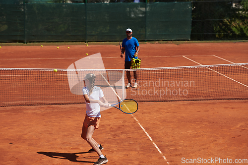 Image of A professional tennis player and her coach training on a sunny day at the tennis court. Training and preparation of a professional tennis player