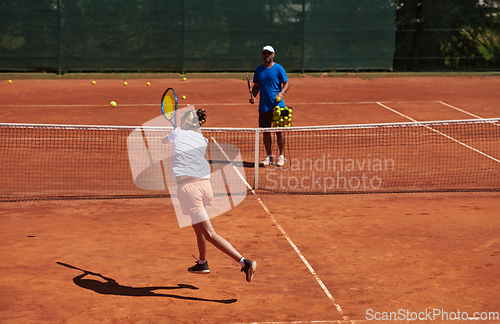 Image of A professional tennis player and her coach training on a sunny day at the tennis court. Training and preparation of a professional tennis player