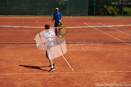 Image of A professional tennis player and her coach training on a sunny day at the tennis court. Training and preparation of a professional tennis player