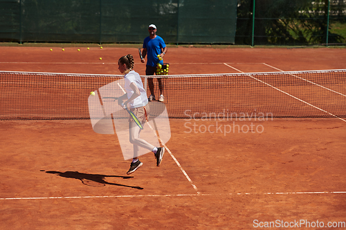 Image of A professional tennis player and her coach training on a sunny day at the tennis court. Training and preparation of a professional tennis player