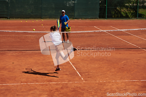 Image of A professional tennis player and her coach training on a sunny day at the tennis court. Training and preparation of a professional tennis player