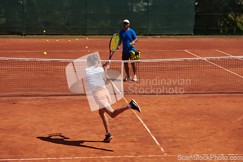 Image of A professional tennis player and her coach training on a sunny day at the tennis court. Training and preparation of a professional tennis player