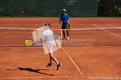 Image of A professional tennis player and her coach training on a sunny day at the tennis court. Training and preparation of a professional tennis player