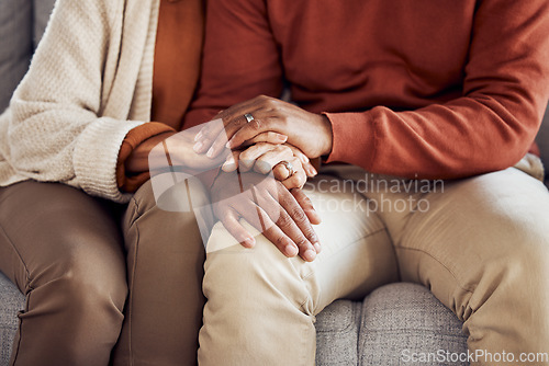 Image of Black couple, holding hands on sofa or comfort support, care and love bonding together in home living room. Black man, black woman sitting couch and embrace with kindness, trust and help with problem