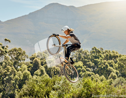 Image of Sport, action and biker doing jump in air with mountain bike for extreme sports, adrenaline and hobby. Fitness, adventure and woman on bike doing trick shot, jumping and stunt on bicycle in nature
