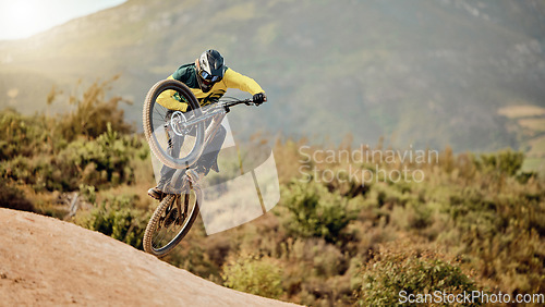 Image of Bicycle, biker and jump in air for competition, mountain biking and extreme sport with helmet, outdoor and in nature. Athlete, bike and cycling for fun, freedom and health for adventure and wellness