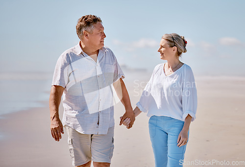 Image of Beach, love and senior couple holding hands while walking for health, exercise and wellness. Happy, romance and elderly man and woman on romantic walk together in nature by ocean or sea in Australia.