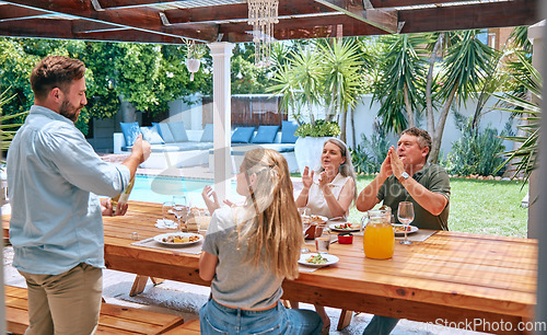 Image of Champagne, celebration and family with applause at lunch party with food, love and relax in garden of house. Wine, happy and man with alcohol at barbecue with woman and senior parents in a backyard