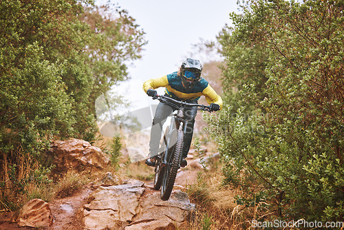 Image of Fitness, sports and man cycling in nature on a bicycle for training, workout and exercise outdoors alone. Focus, healthy and fast athlete rides a bike with speed downhill on a wet rocky path or trail