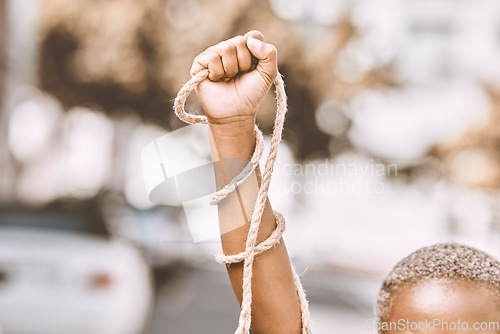 Image of Hand, rope and fist protest slavery for freedom and human rights against an urban background. Activist, activism and rebellion against racism and change for civil, law and government rights