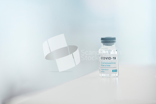 Image of Covid, vaccine and medication with a bottle of a liquid on a table in the hospital as a cure or treatment. Healthcare, pharmacy and medicine in a corona research lab for pharmaceutical development