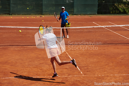 Image of A professional tennis player and her coach training on a sunny day at the tennis court. Training and preparation of a professional tennis player