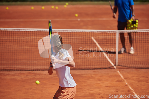 Image of A professional tennis player and her coach training on a sunny day at the tennis court. Training and preparation of a professional tennis player